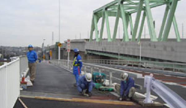 橋梁のジョイント鉄板にノンスキッドコーティングを施工する作業現場のイメージ